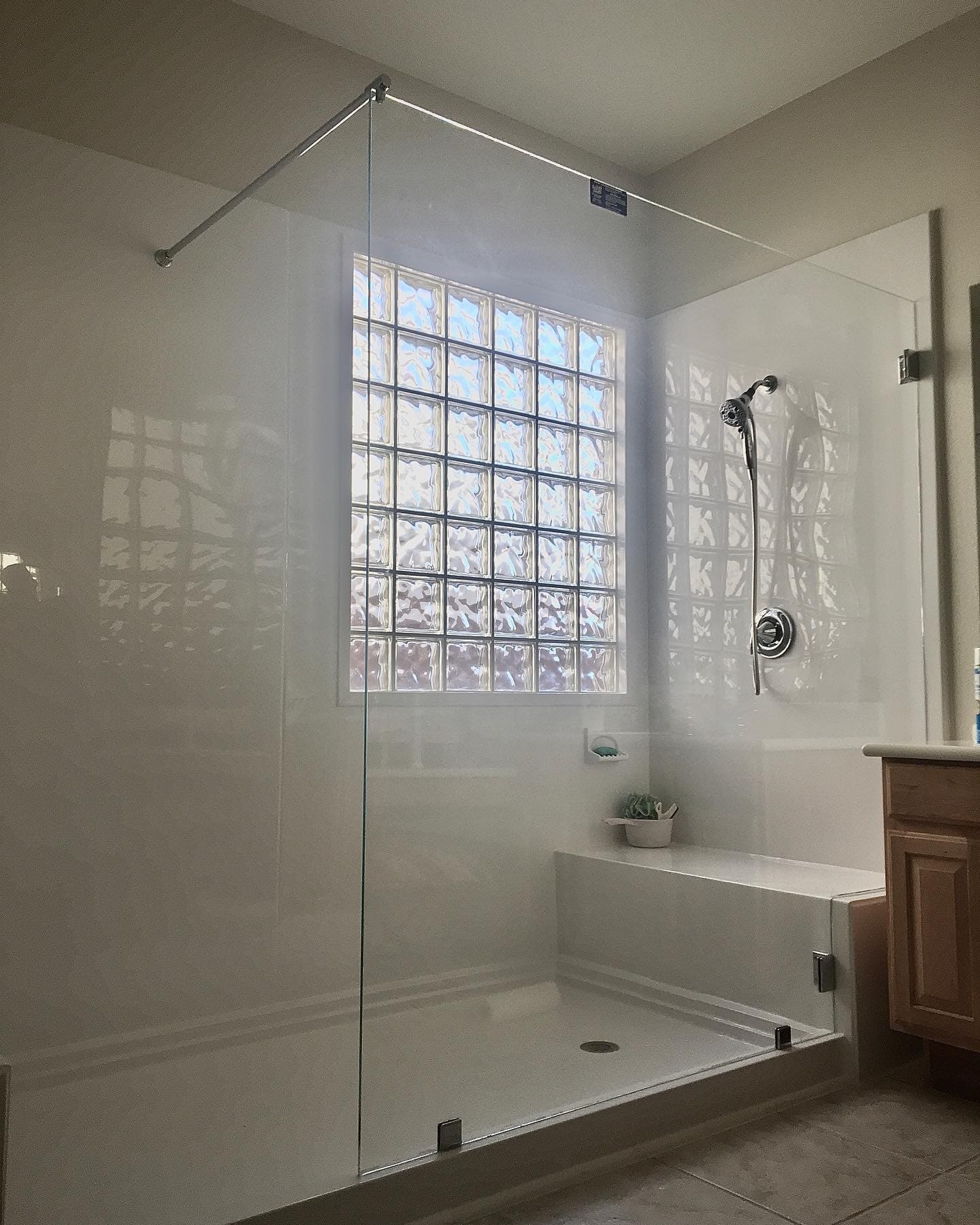 Clear glass fixed panel shower enclosure with chrome support bar and glass block window in a Las Vegas Valley bathroom