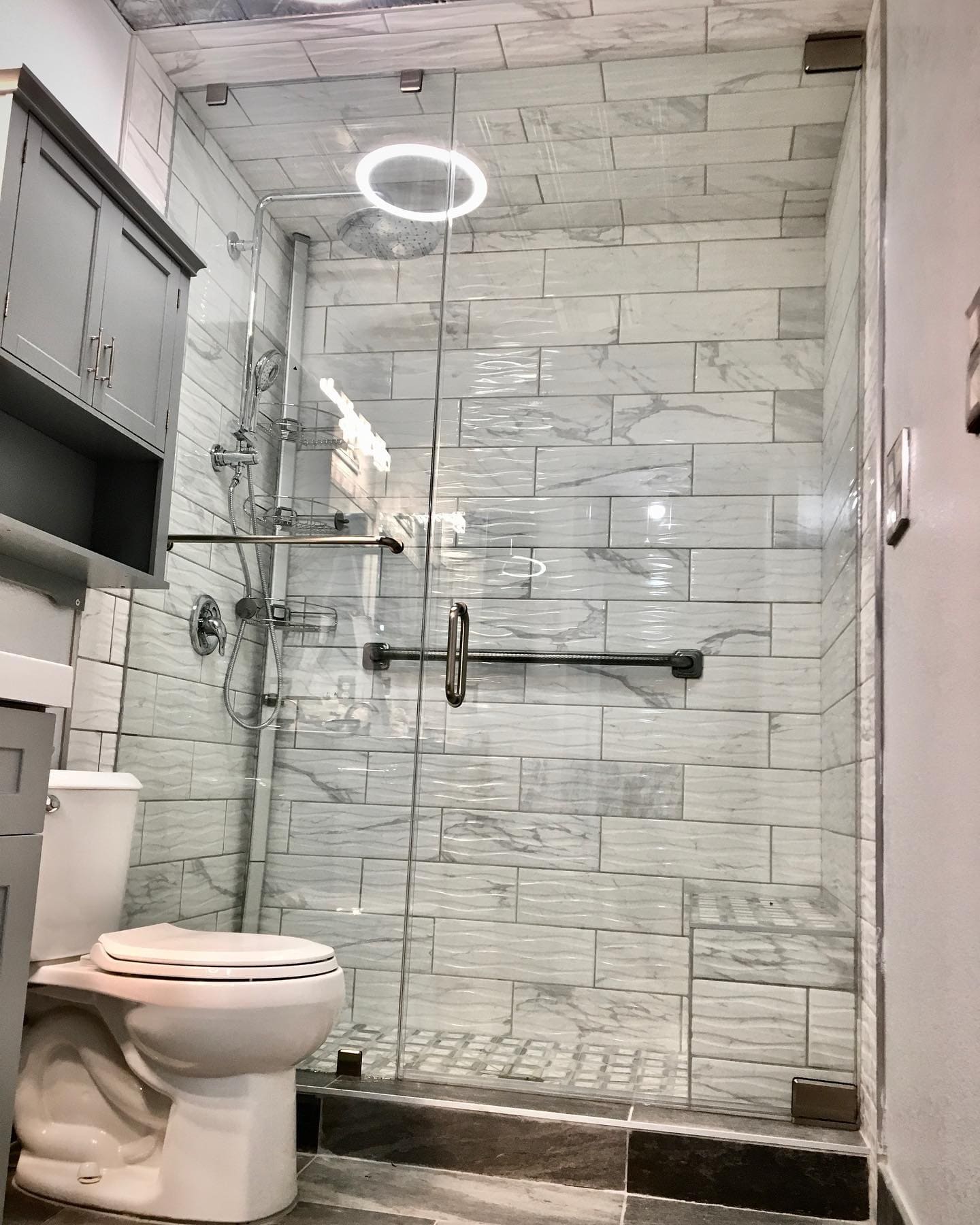 Frameless glass shower door with towel bar on marble tile walk-in shower with chrome hardware installed in a Las Vegas bathroom